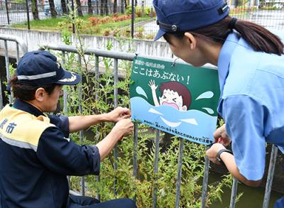 啓発看板を設置する市職員と高槻警察署員