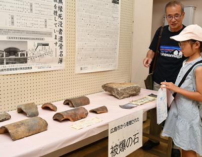 原子爆弾の被害を紹介する展示物をみる来場者