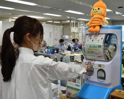 「緑の募金」カプセルトイマシンを回す来庁者