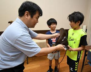 学芸員から兜を受け取る小学生